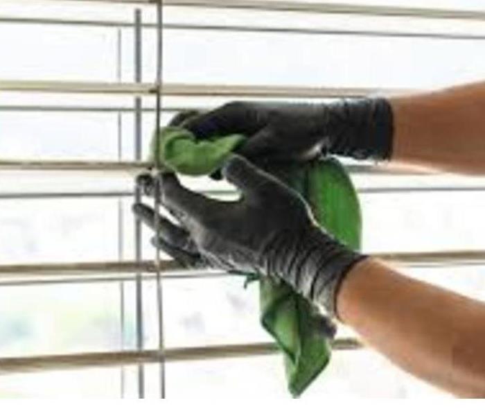 Cleaning window blinds with a rag 